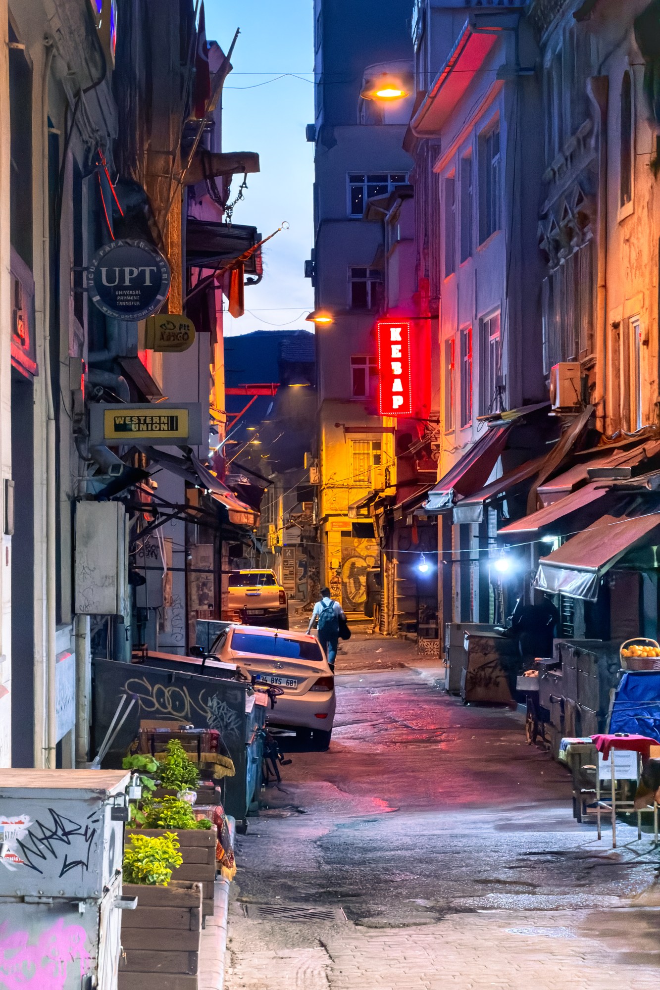 Calle estrecha de Estambul con letreros y luces al anochecer · iPhone 17 Pro
