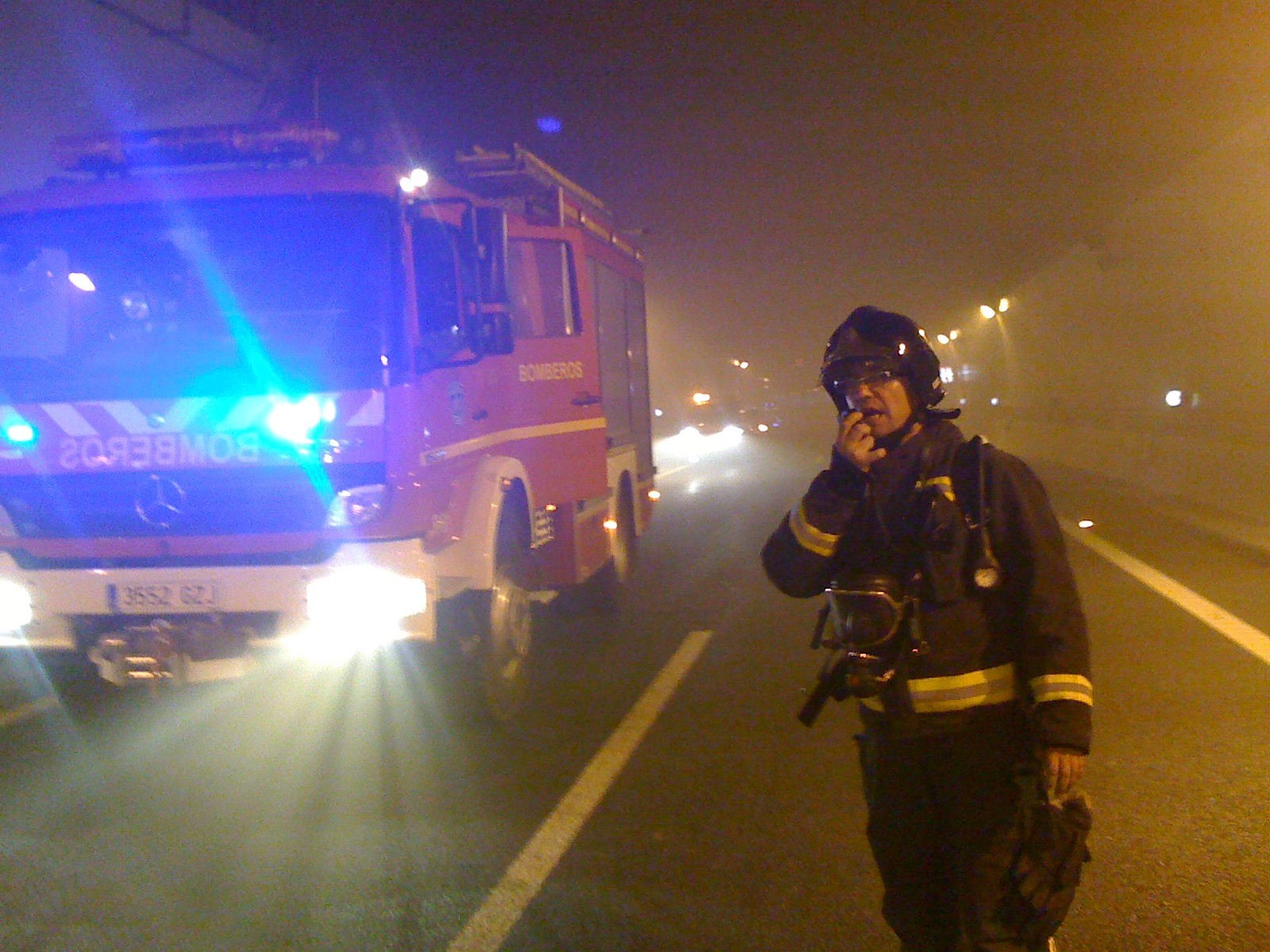 Bombero y vehículo de emergencias en una escena nocturna con poca luz · iPhone 3G